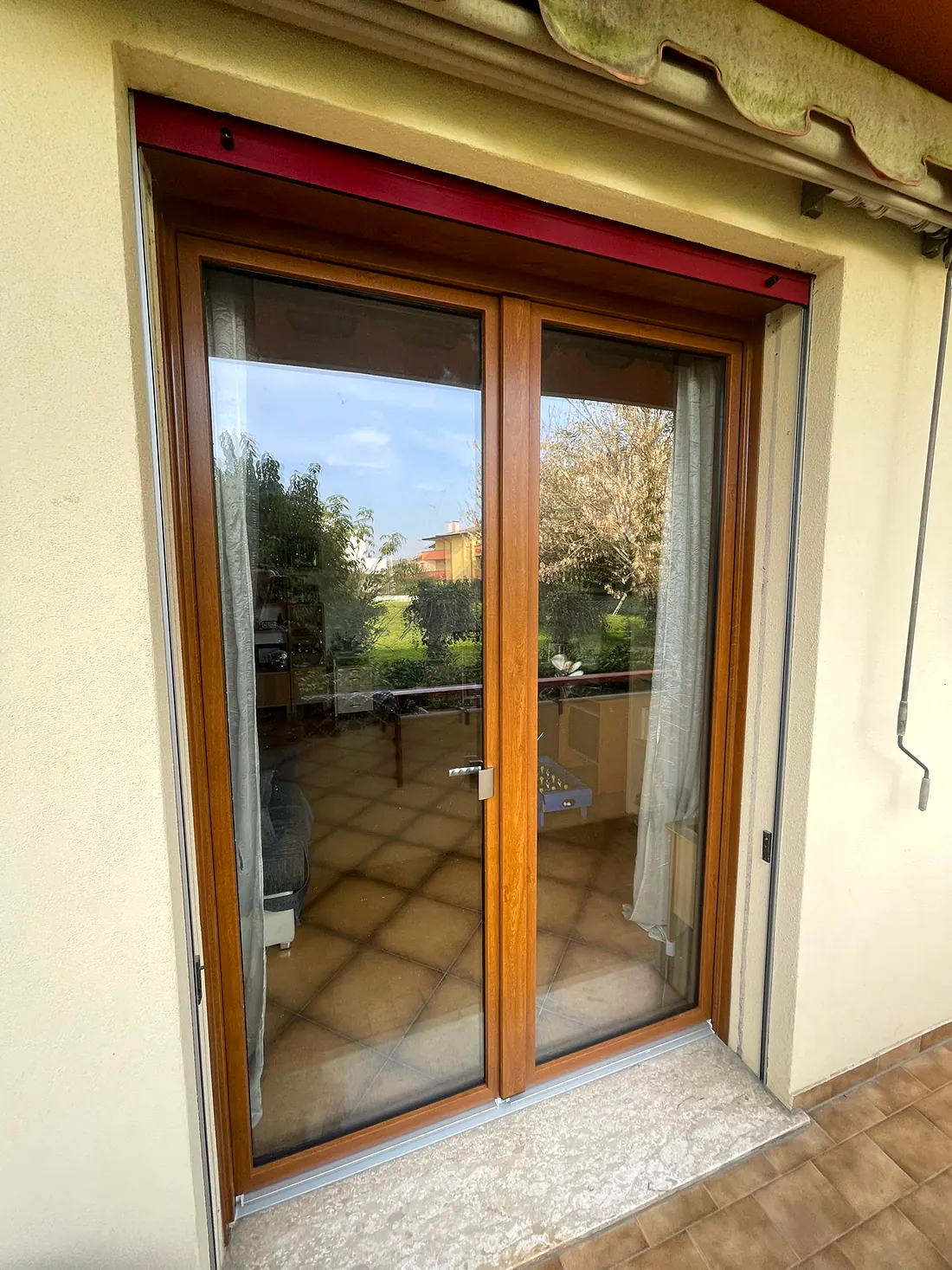 Portafinestra tutto vetro a due ante effetto legno con vista sul giardino