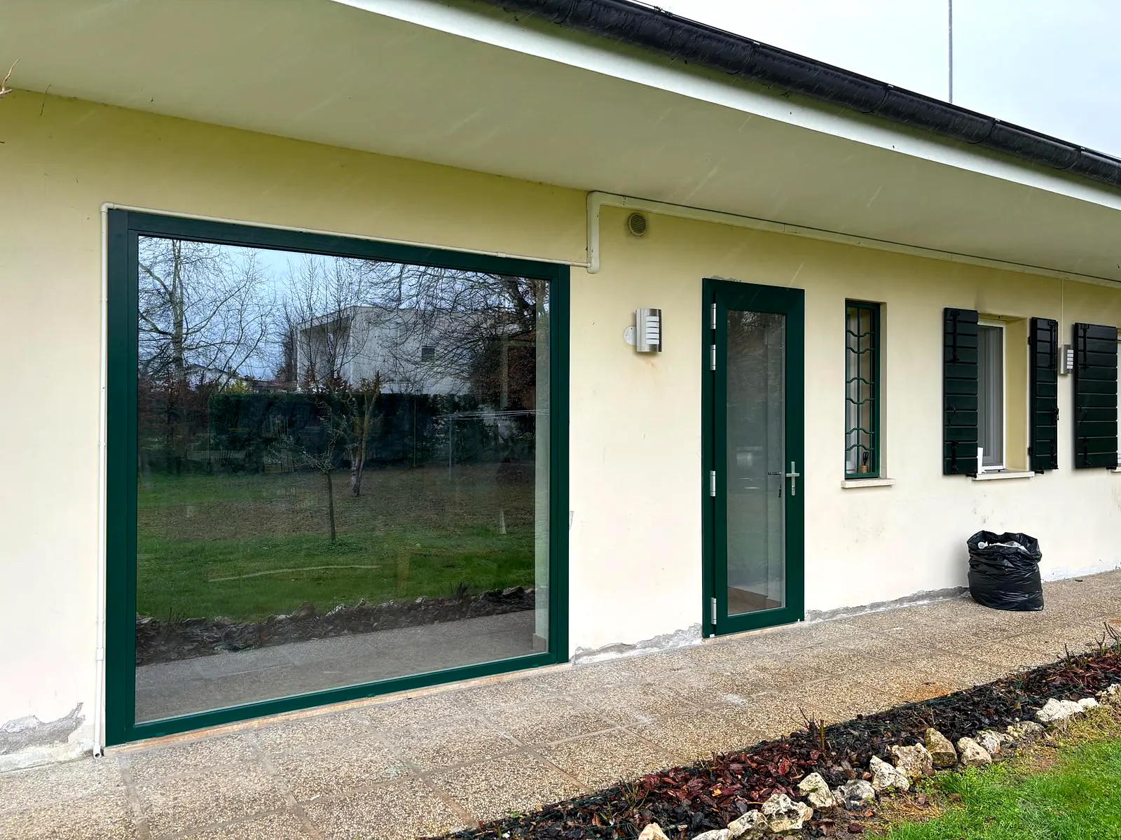 Casa con finestre e porte-finestre verdi lungo il porticato